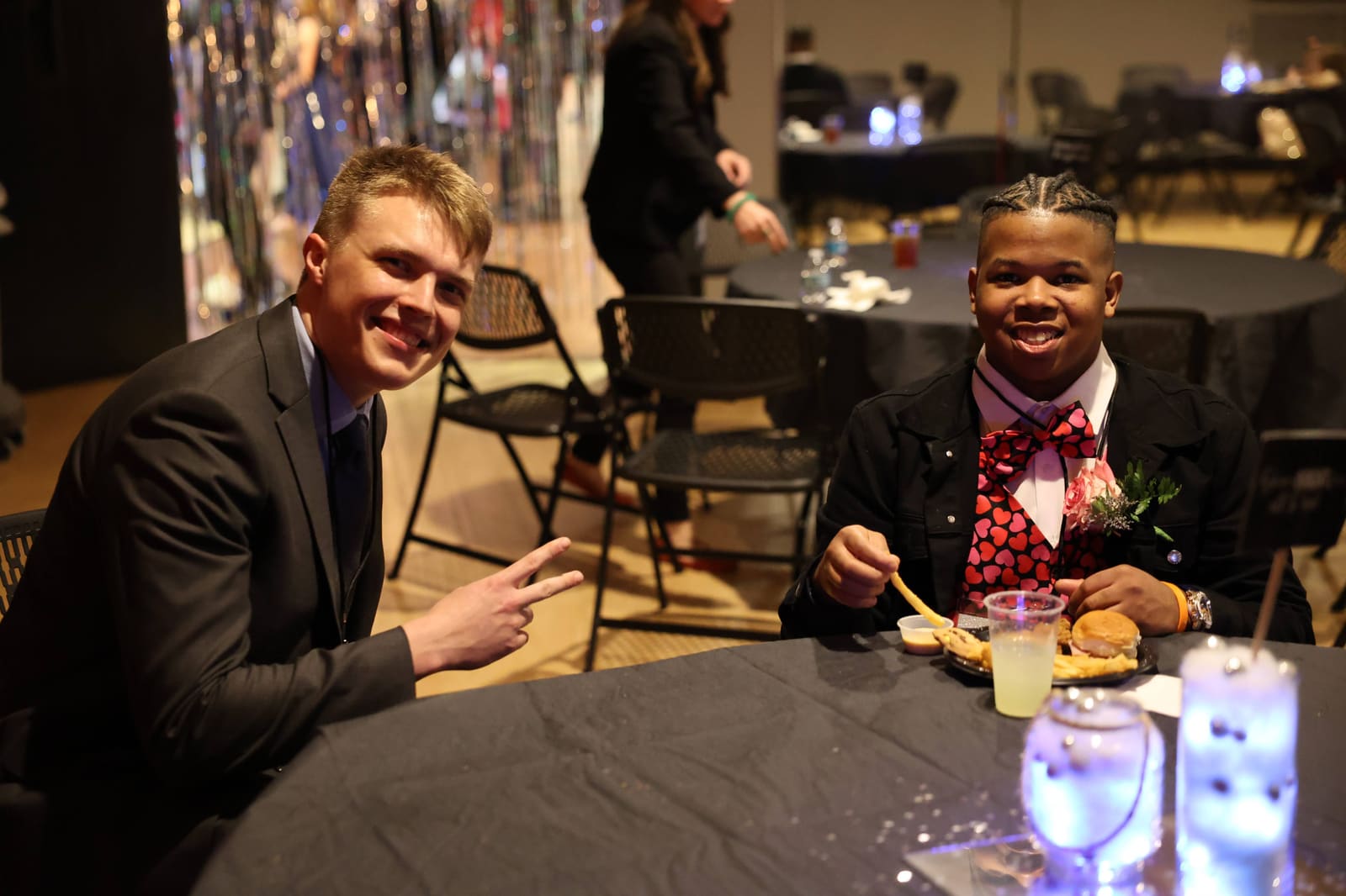 A guest and his buddy at a dinner table, smiling.