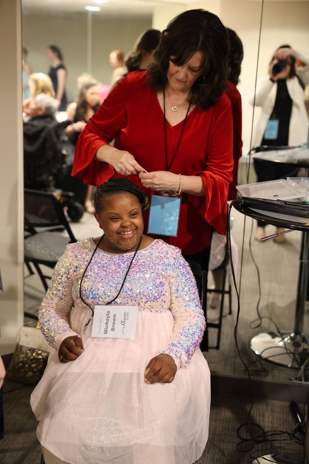 A volunteer doing a smiling guest's hair before the dance.
