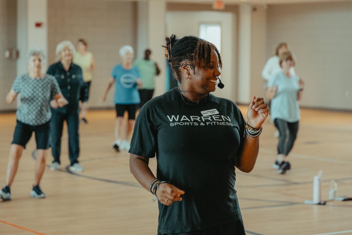 An instructor in a Warren Sports & Fitness shirt leading a class.