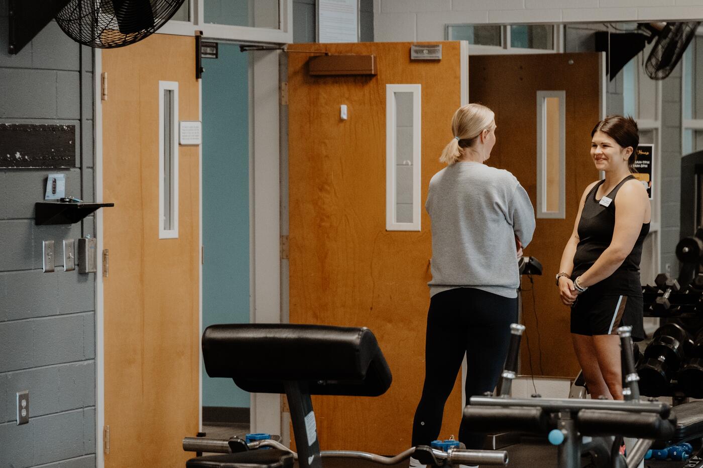 Two people talking at the weight room door.